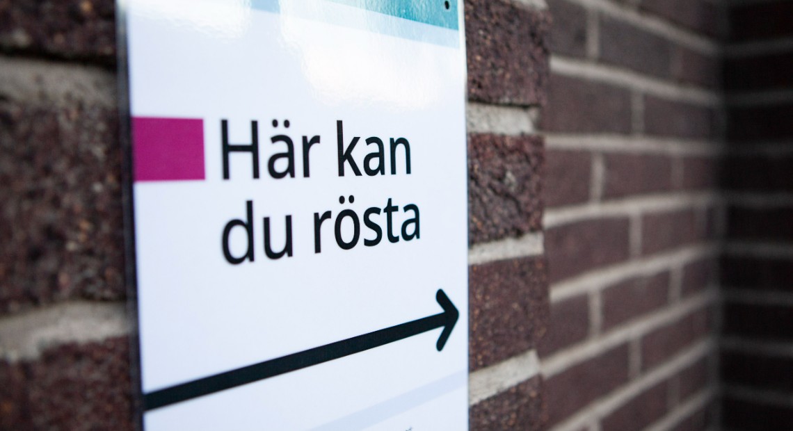 Foto på tegelvägg med skylt med texten "Här kan du rösta"